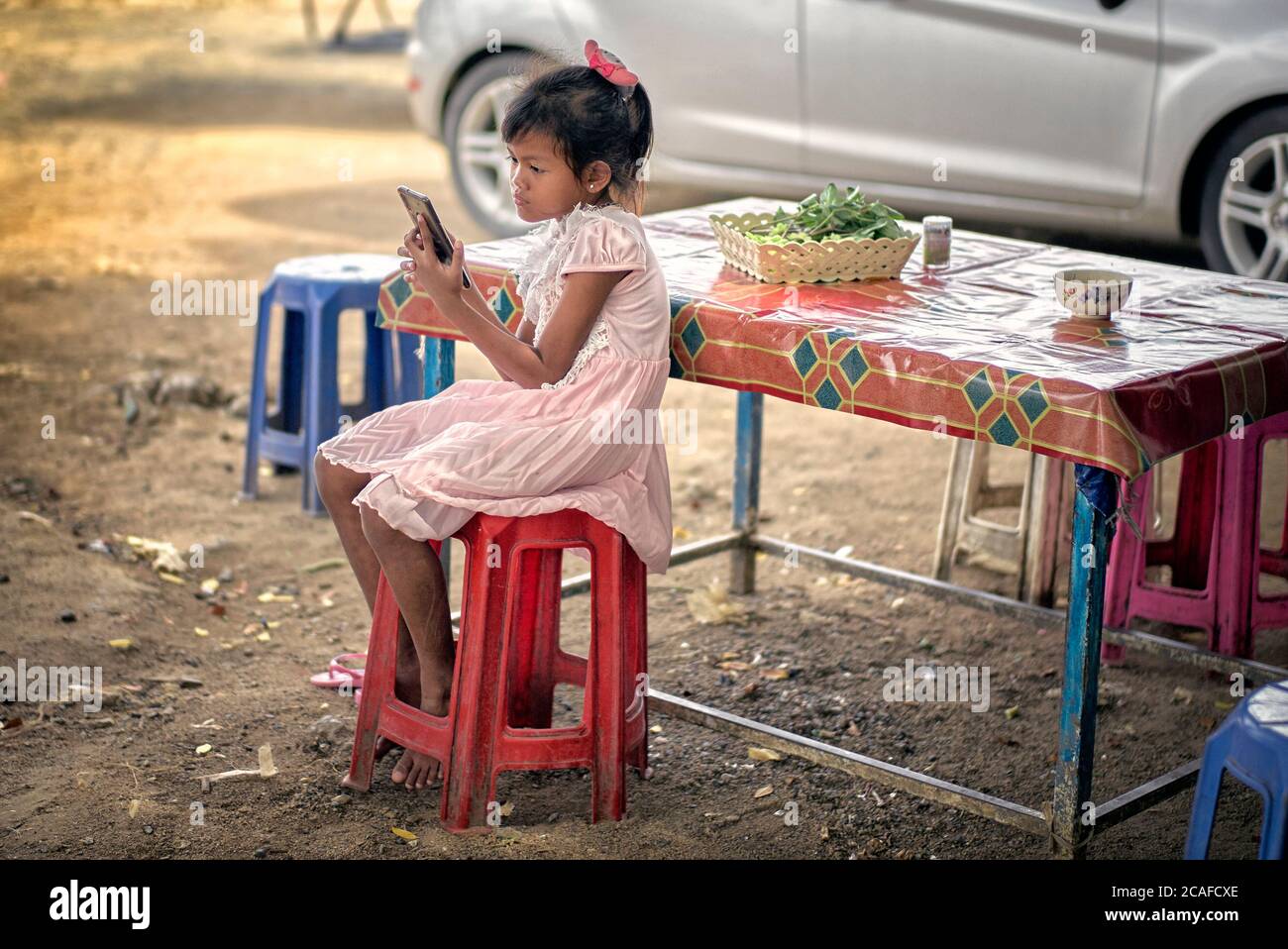 Niño solo con smartphone que se aleja el aburrimiento de las restricciones de Coronavirus que causan el cierre de la escuela y el distanciamiento social. Tailandia Sureste de Asia Foto de stock