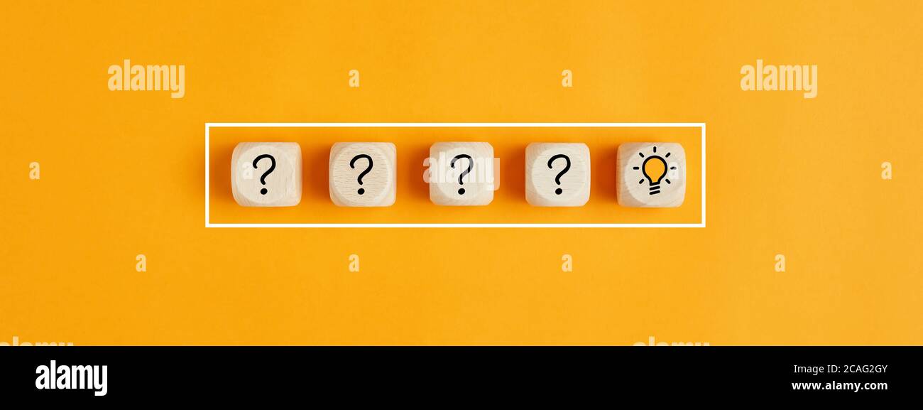 El proceso de resolución de problemas o formación de ideas. Signo de interrogación e iconos de bombilla sobre cubos de madera sobre fondo amarillo. Foto de stock