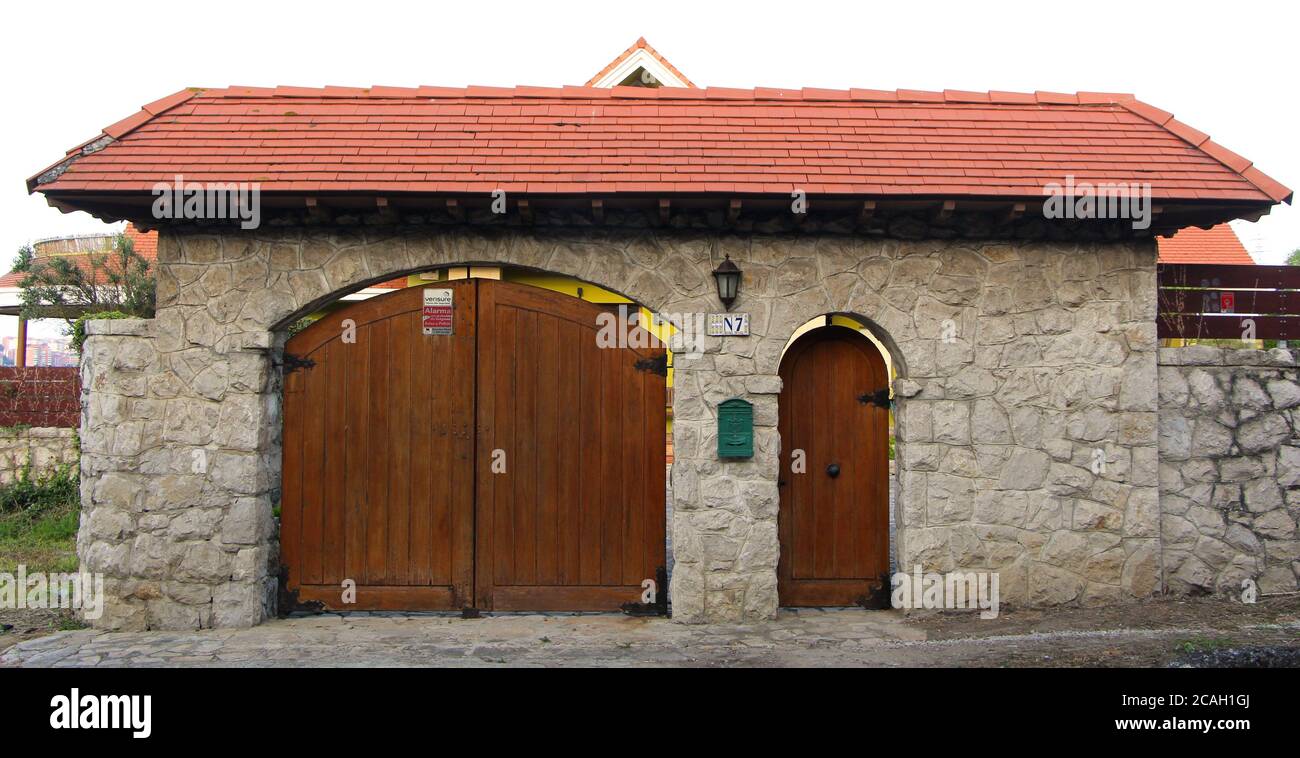 Puerta cubierta y entrada de garaje una casa en Cueto Cantabria España con techo de tejas rojas y pared de piedra Fotografía de Alamy