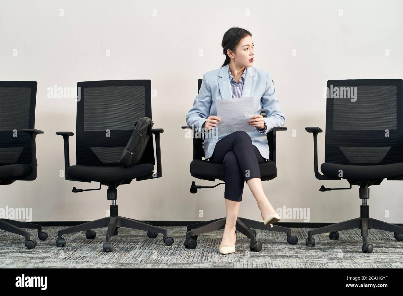 joven mujer asiática buscada de trabajo sentado en la silla ansiosamente esperando la entrevista Foto de stock