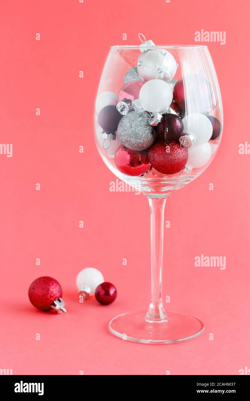 Bolas de Navidad en una copa de vino en un rojo claro primer plano de fondo Foto de stock