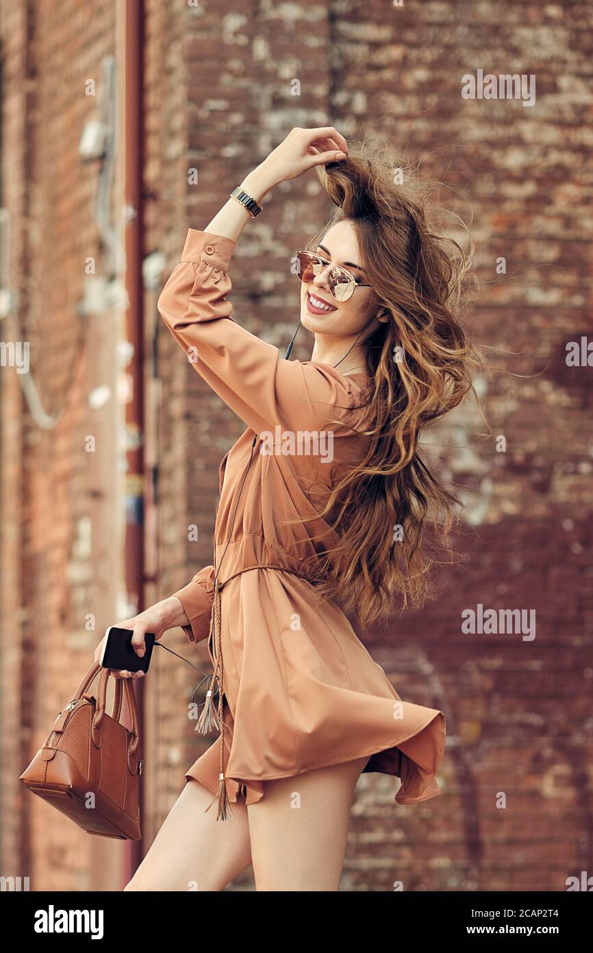 Joven mujer feliz caminando en la calle con vestido corto escuchar la  música y bailar Fotografía de stock - Alamy