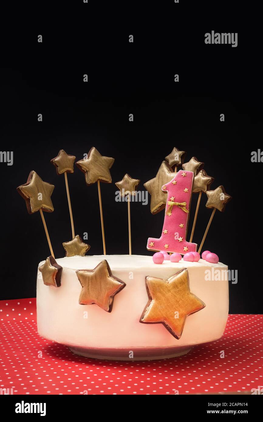 Pastel de cumpleaños decorado con el número 1 de rosa y estrellas de oro de  pan de jengibre sobre un fondo oscuro Fotografía de stock - Alamy