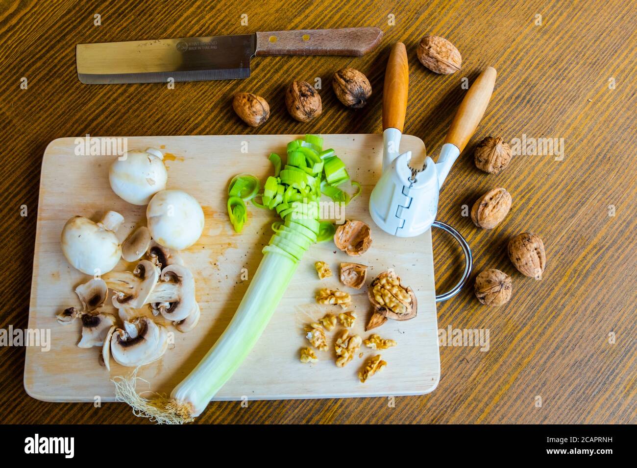 Mesa con productos dietéticos vegetarianos incluyendo nueces, hongos y puerro Foto de stock