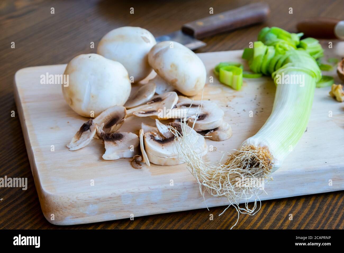 Mesa con productos dietéticos vegetarianos incluyendo nueces, hongos y puerro Foto de stock