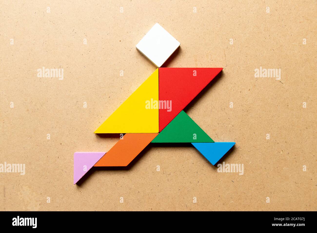 Color tangram rompecabezas en forma hombre corriendo sobre fondo de madera Fotografía stock - Alamy