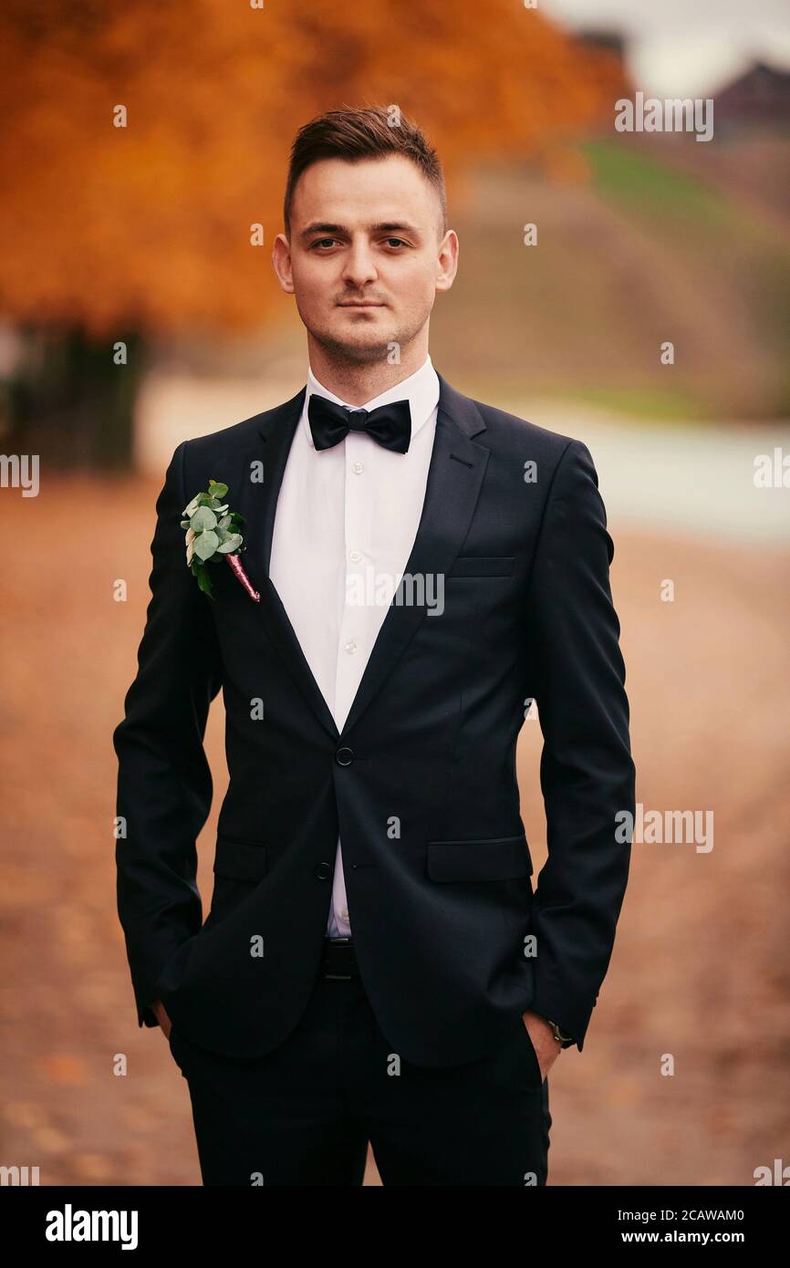 elegante joven novio en traje negro en otoño parque el día de la boda  Fotografía de stock - Alamy