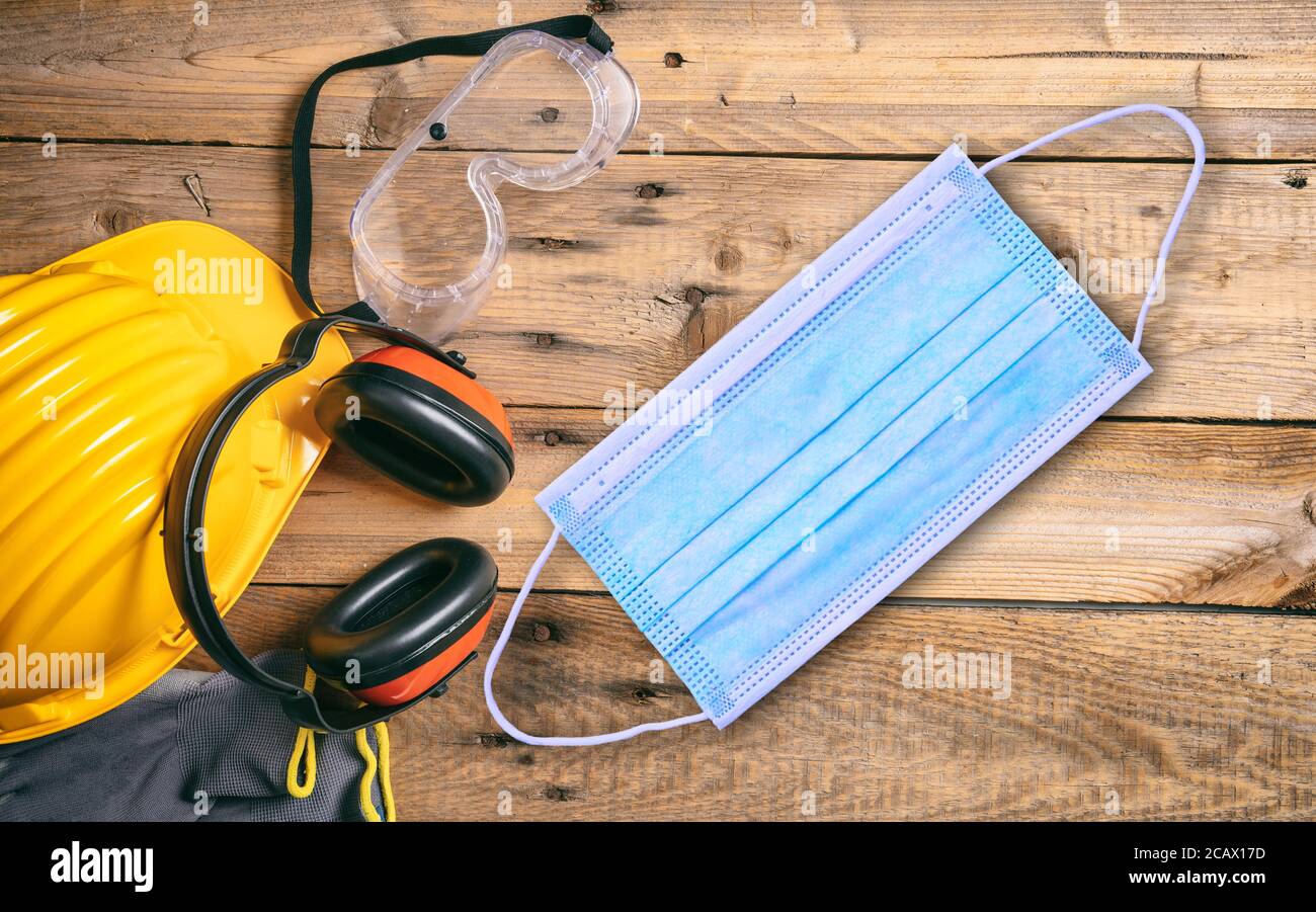 Seguridad en el trabajo y coronavirus. Mascarilla protectora y herramientas de seguridad para obra, fondo de mesa de madera. Prevención de la enfermedad de COVID19. Foto de stock