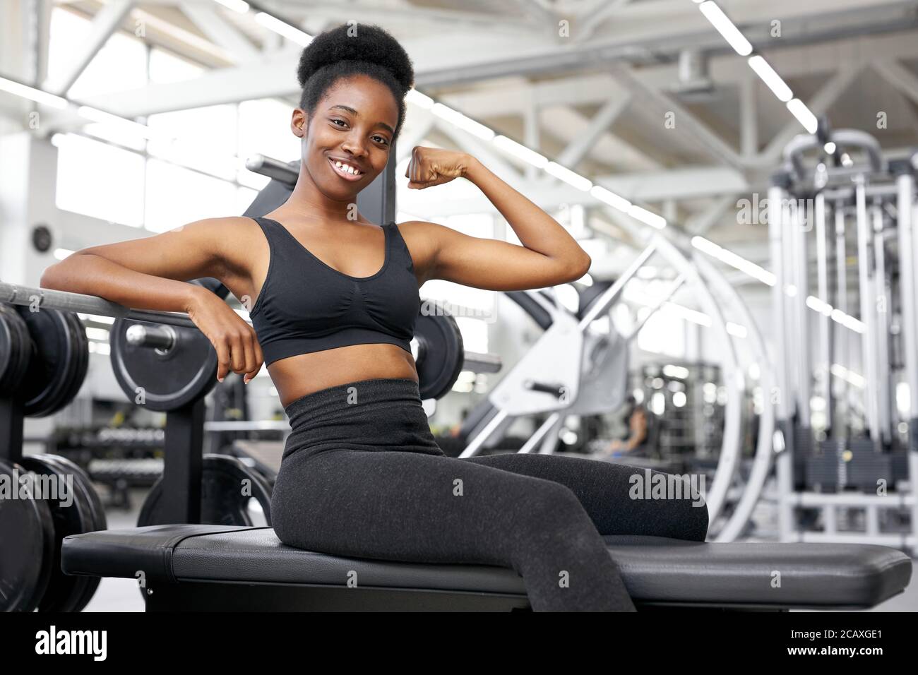 mujer bastante feliz descansando después de entrenar en el gimnasio,  disfrutar del deporte. siéntese solo mostrando los músculos del brazo,  mirando la cámara Fotografía de stock - Alamy