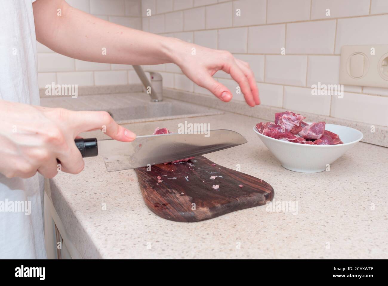 mujer de carne en el tablero de la cocina en la cocina blanca Foto de stock