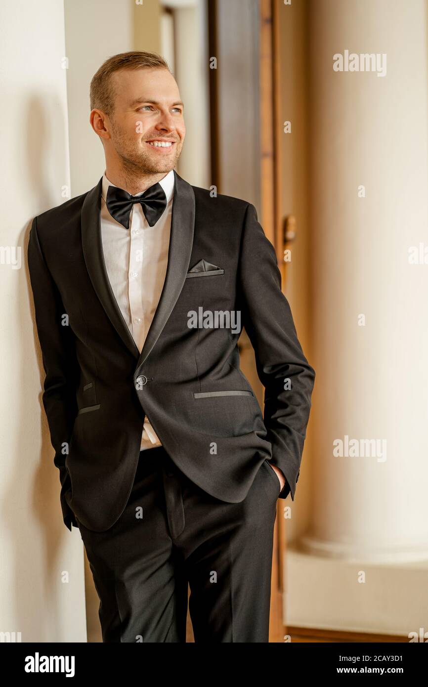 joven hombre caucásico sonriente en tuxedo, guapo en traje formal con lazo  posando, mirando lado. antes de la actuación en el teatro Fotografía de  stock - Alamy
