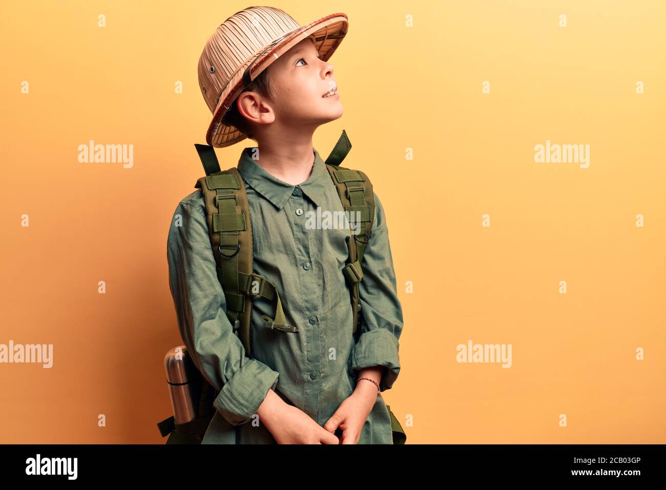 Lindo niño rubio con sombrero explorador y mochila mirando al lado
