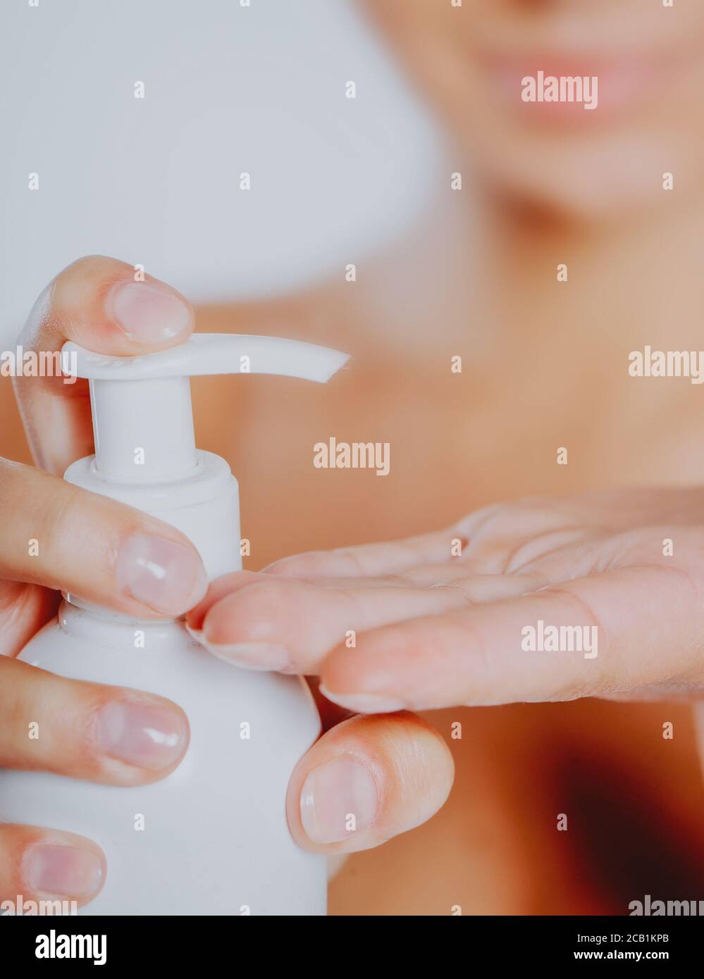 Mujer presionando el jabón líquido en su mano. Botella de jabón blanco con dispensador en la mano. Foto de stock