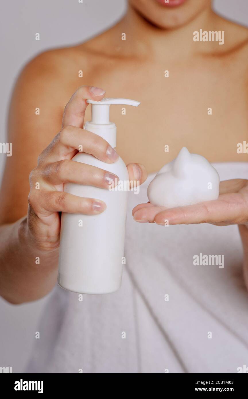 Mujer presionando el jabón líquido en su mano. Botella de jabón blanco con dispensador en la mano. Foto de stock
