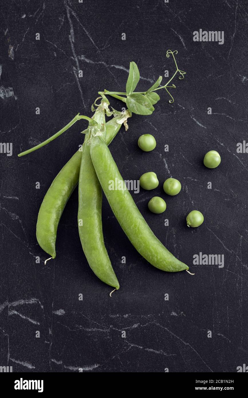 Guisantes frescos cosechados en mármol negro desde arriba Foto de stock