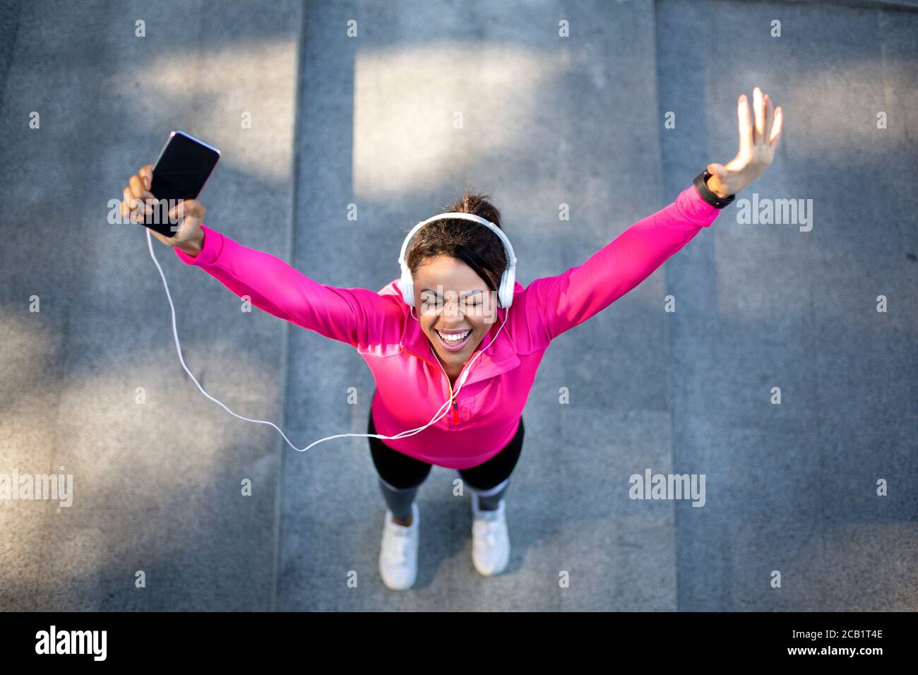 Vista superior de la mujer emocional jogger sosteniendo el smartphone Foto de stock