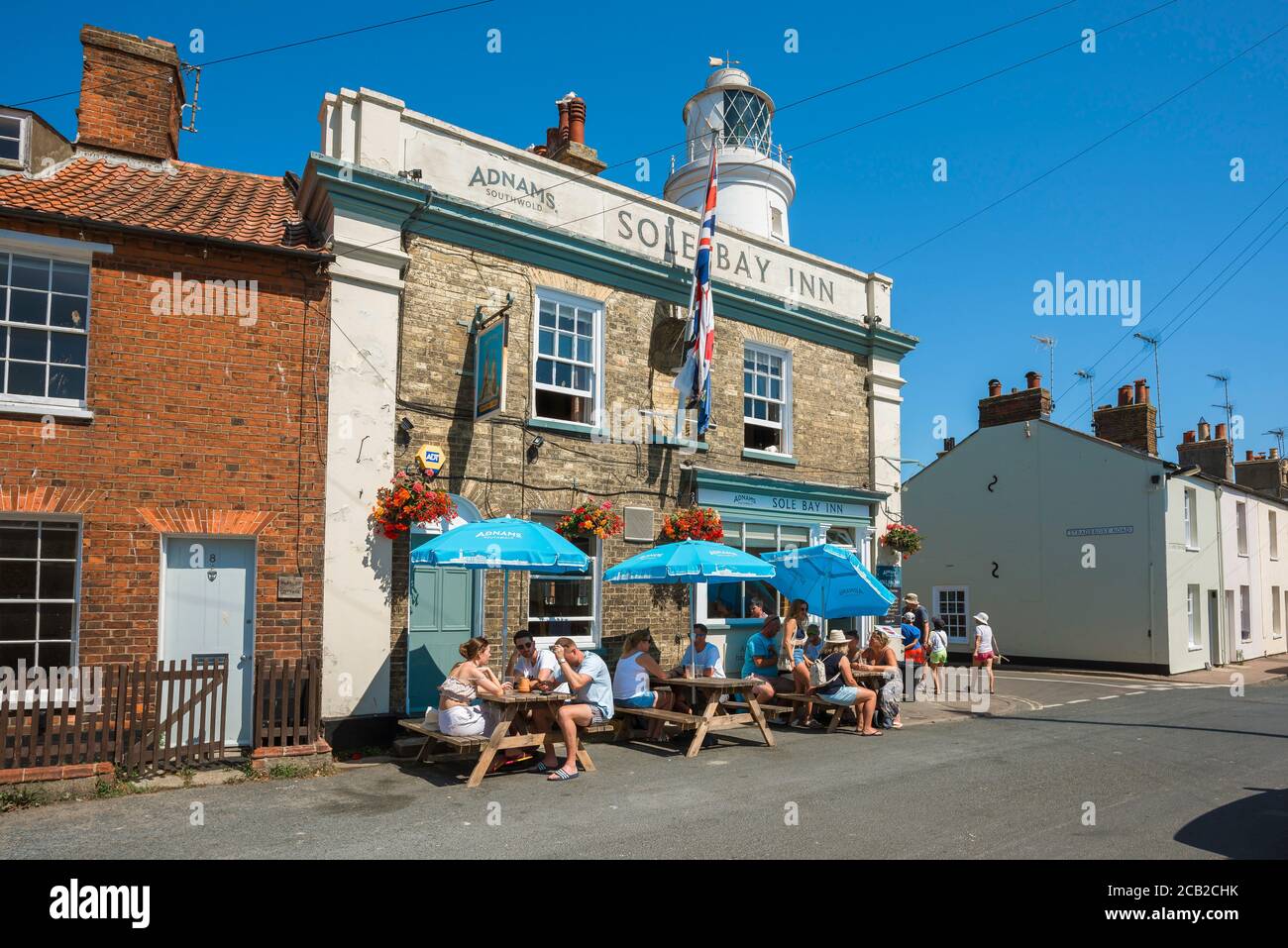 Southwold Suffolk, vista en verano de la gente bebiendo fuera de la casa pública de Sole Bay Inn en la ciudad costera de Southwold, Suffolk, Reino Unido Foto de stock