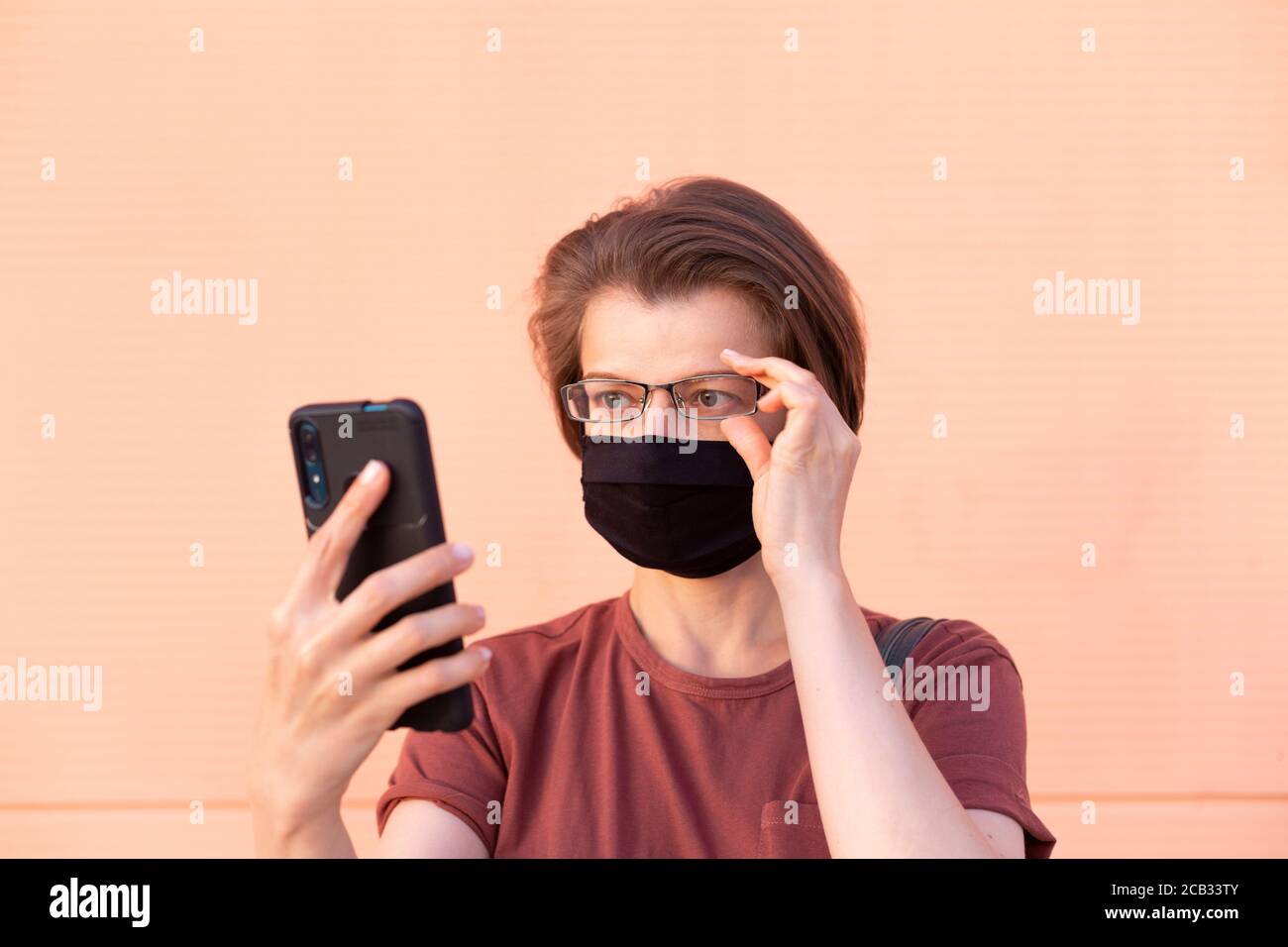 Retrato de una mujer en una máscara médica sosteniendo un teléfono. Foto de stock