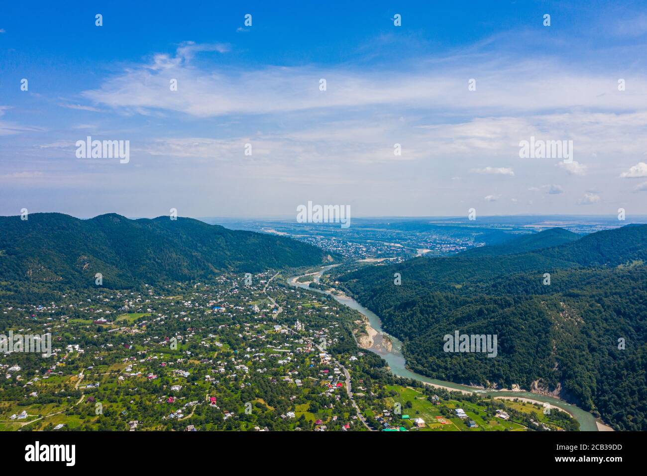 Vista aérea de la montaña verde, bosque de pinos, río y pueblo. Cárpatos, Ucrania. Foto de stock