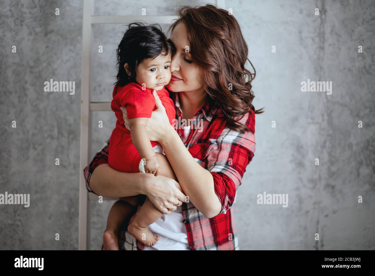 hermosa madre joven besando a su adorable hijo, sensación cálida, emoción, conceptos de cercanía Foto de stock