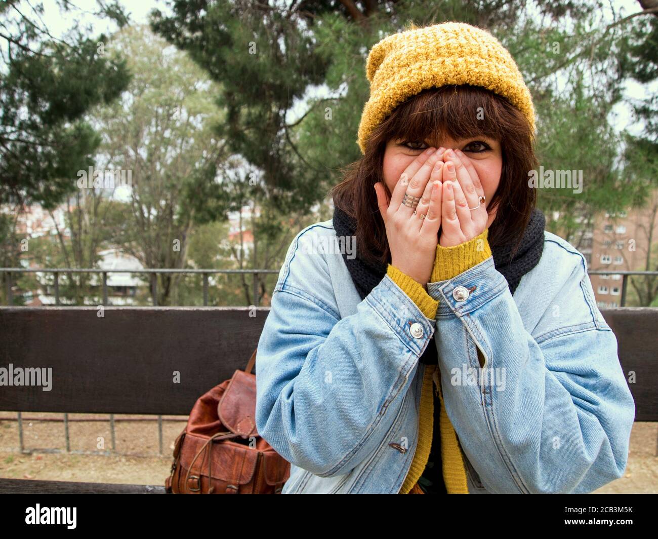 Mujer joven con gorra de lana amarilla sentada en un banco que cubre su cara  con sus manos. Concepto urbano de otoño Fotografía de stock - Alamy