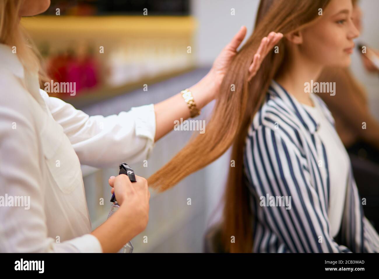 La moderna peluquería tidies el pelo largo de los clientes jóvenes, haciendo el pelo en la víspera de las vacaciones. Transformación completa en salón de belleza Foto de stock
