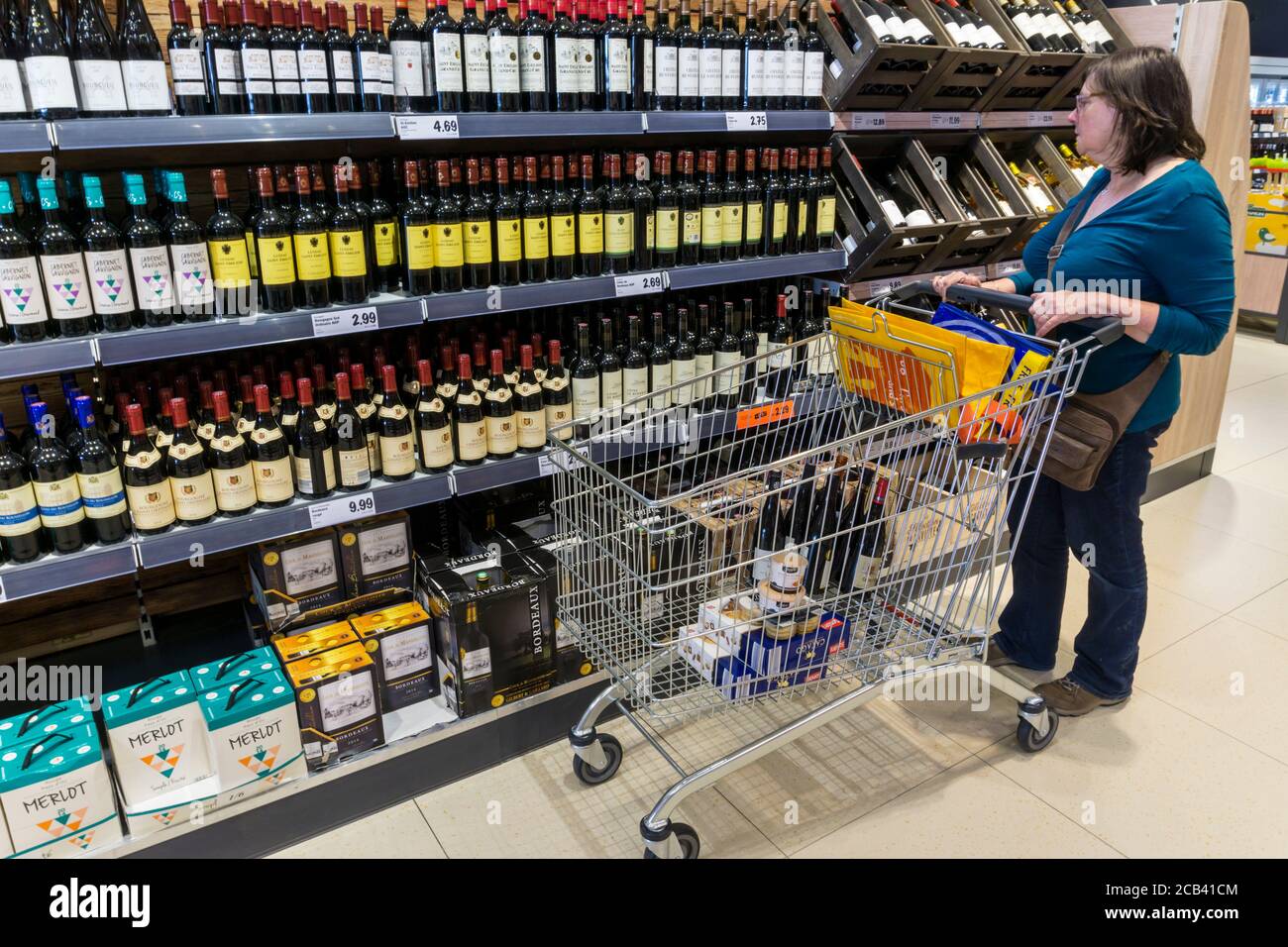 Mujer mirando la selección de vino disponible para la venta en las estanterías de un supermercado francés Lidl. Foto de stock