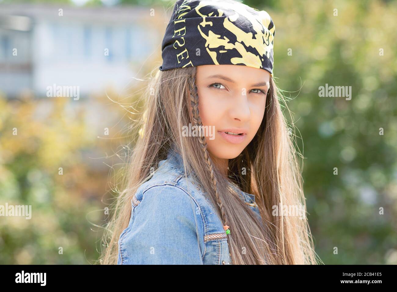 Mujer adolescente bastante moderna con el pelo largo usando bandana y..  mirando seriamente la cámara al aire libre bajo la luz del sol Fotografía  de stock - Alamy