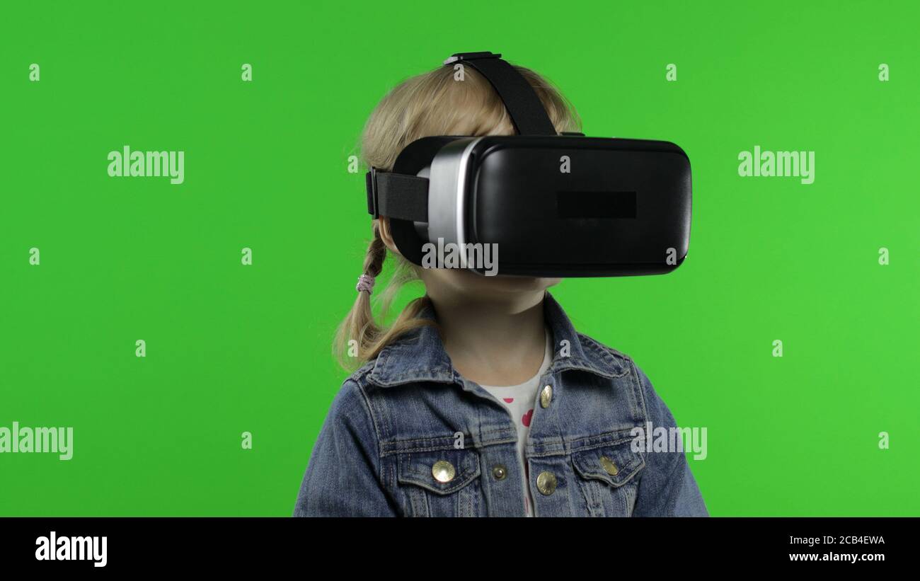 Niña pequeña usando el casco de auriculares VR para jugar. Viendo vídeo de  realidad virtual en 3d 360. Aislado sobre fondo verde clave chroma en el  estudio. Tecnología del futuro. Niño en