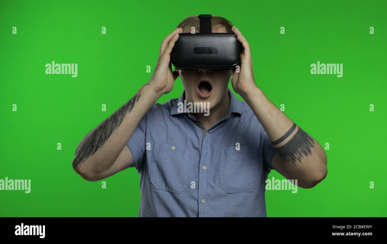 Hombre asombrado usando el casco de auriculares de la aplicación VR para  jugar juego de simulación, dibujo. Viendo vídeo de realidad virtual en 3d  360. Aislado sobre fondo verde clave chroma en