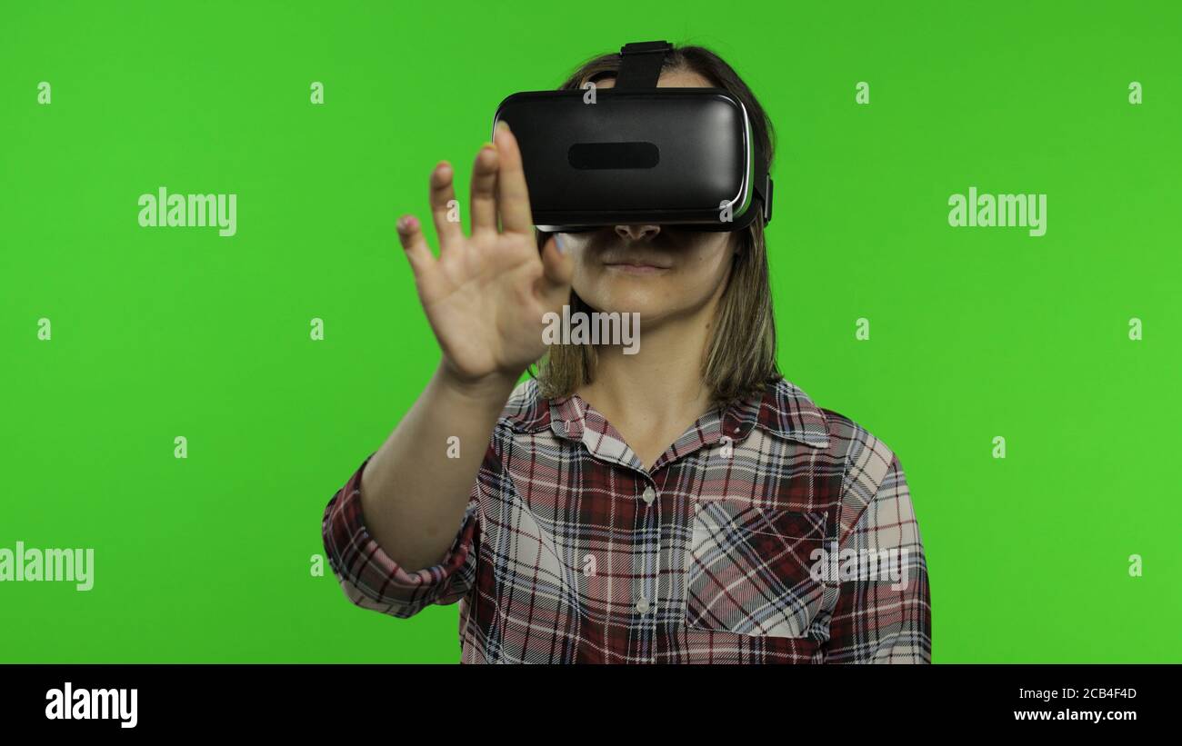 Mujer en el casco de auriculares de VR juega el juego. Pulsa los botones  con los dedos. Viendo vídeo de realidad virtual en 3d 360. Aislado sobre  fondo de clave de croma.