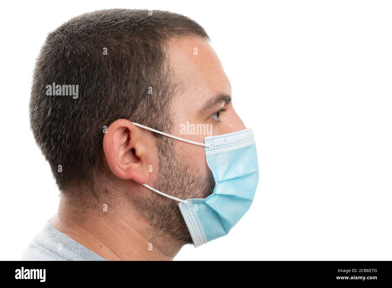 Vista lateral del hombre adulto que lleva una mascarilla quirúrgica o médica desechable para prevenir la contaminación de la gripe del coronavirus del sars con una copia en blanco área para adve Foto de stock