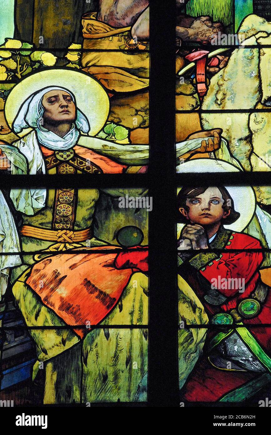 El patrón checo san Wenceslao, duque de Bohemia, se arrodilla en la niñez para rezar con su abuela, San Ludmila, en los años 30 vitrales del mundialmente famoso artista Art Nouveau Alphonse Mucha en la capilla del nuevo arzobispo de la Catedral de Praga, República Checa. La ventana completa es una alegoría de Cristo bendiciendo a las naciones eslavas y cuenta con ‘Slavia’, una encarnación femenina del pueblo eslavo, así como escenas de la vida de los Santos Cirilo y Metodio, misioneros del siglo IX a los eslavos. Foto de stock