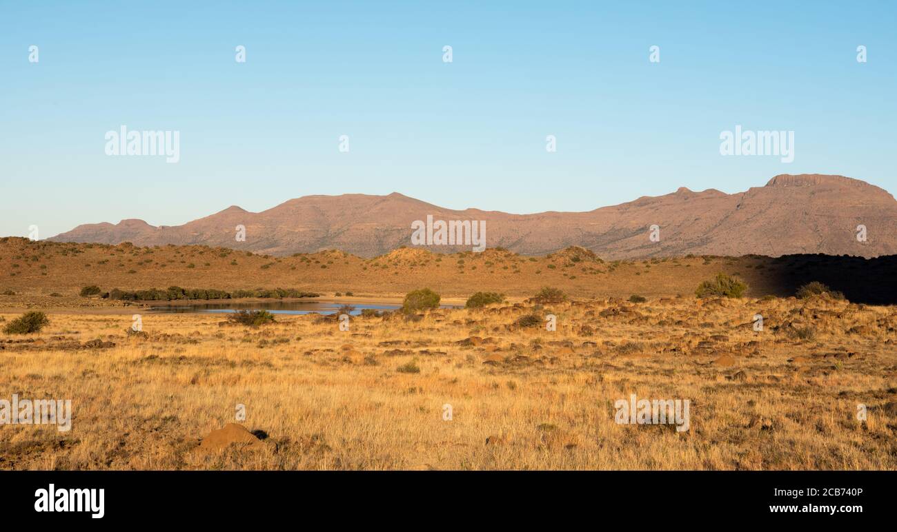 Vista del estanque de tierras de cultivo con colinas y la montaña en el fondo Foto de stock