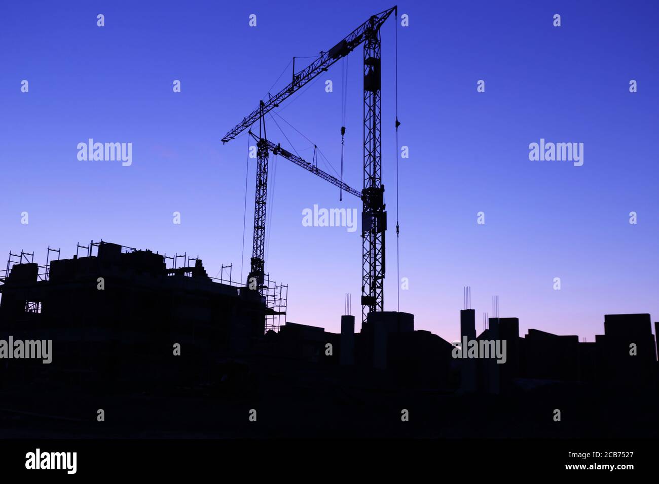 Sitio de construcción con grúas en la caída nocturna Foto de stock