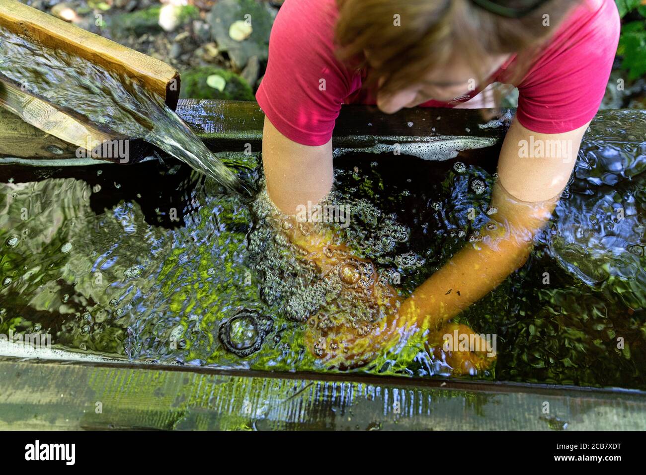 Mujer con baño de brazos, cura Kneipp, hidroterapia en el río, un camino de senderismo temático en Egelsee, Austria Foto de stock