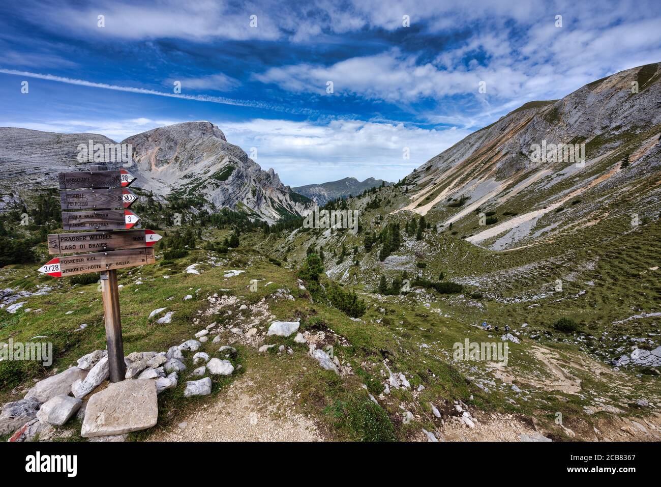 Cuatro excursionistas más allá de una señal de senderismo, Dolomitas, Parque Natural de Fanes-Sennes-Braies, Tirol del Sur, Italia Foto de stock
