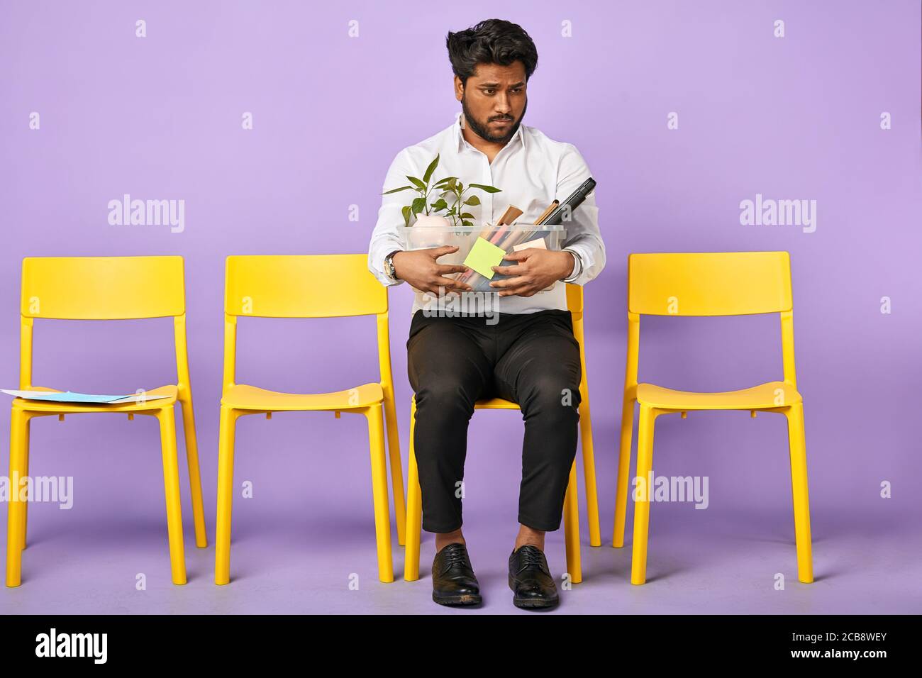 Retrato de triste joven de piel oscura que sostiene caja de personal las pertenencias son despedido del trabajo Foto de stock
