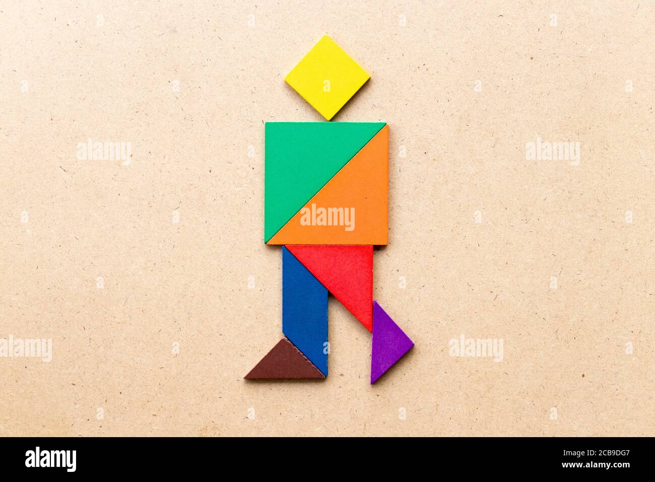 Tangram de color en forma de hombre caminando sobre fondo de madera de stock - Alamy