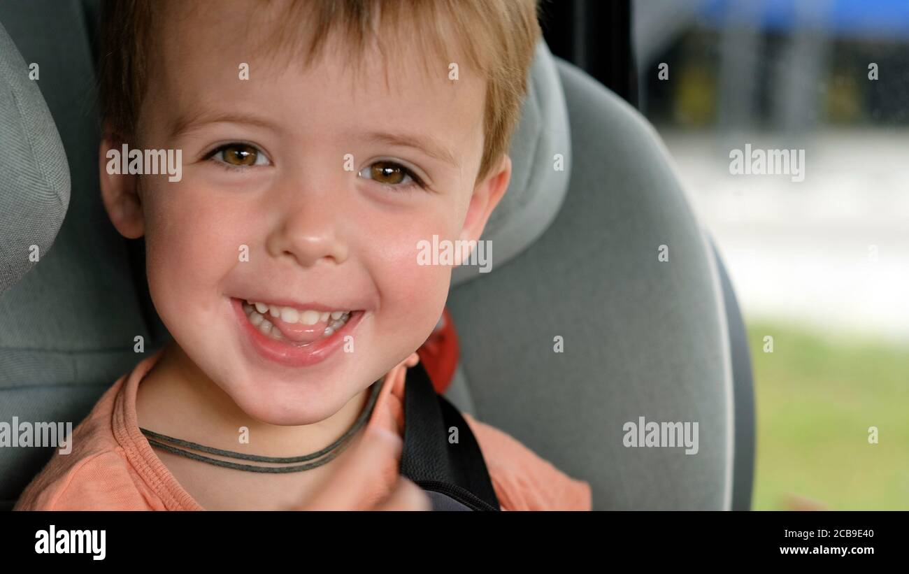 Niño sonriendo mientras está sentado en el asiento del coche Foto de stock