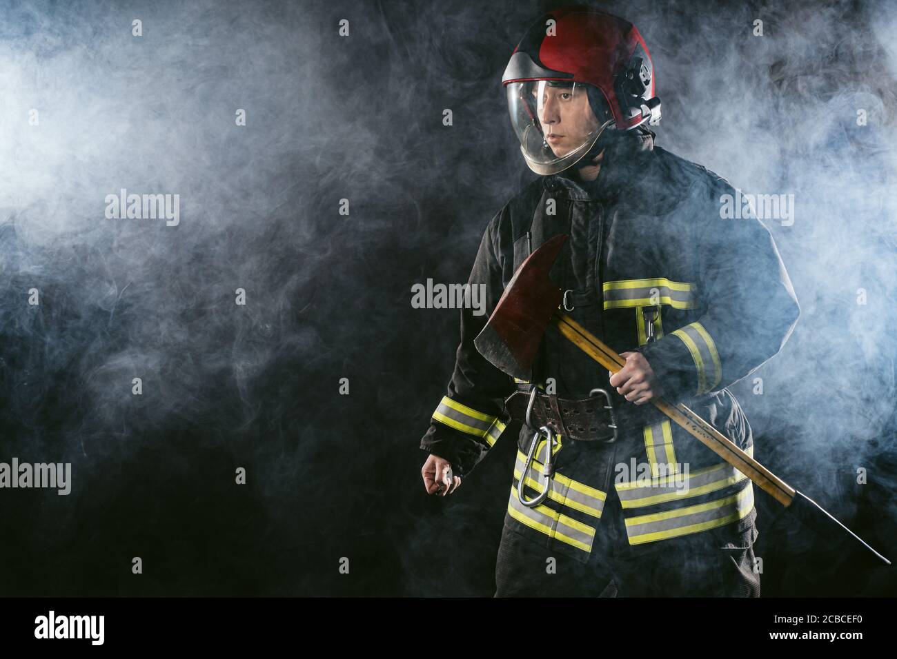 un bombero seguro y resistente que ahorra y protege del fuego, que lleva casco y traje de protección, que trabaja en la estación de bomberos Foto de stock