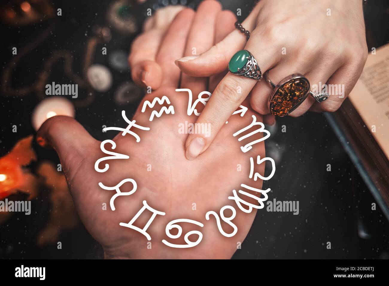 Astrología y esoterismo. El adivino apunta con un dedo a la palma del  hombre. Sobre un fondo negro yacen runas, una vela, amuletos y un libro. La  vi Fotografía de stock -
