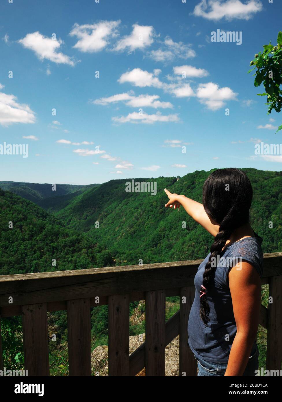 Una mujer afro-asiática vista desde atrás señala el paisaje de montaña.  Durante las vacaciones, a los turistas les gusta tomar un descanso para  admirar lo natural Fotografía de stock - Alamy