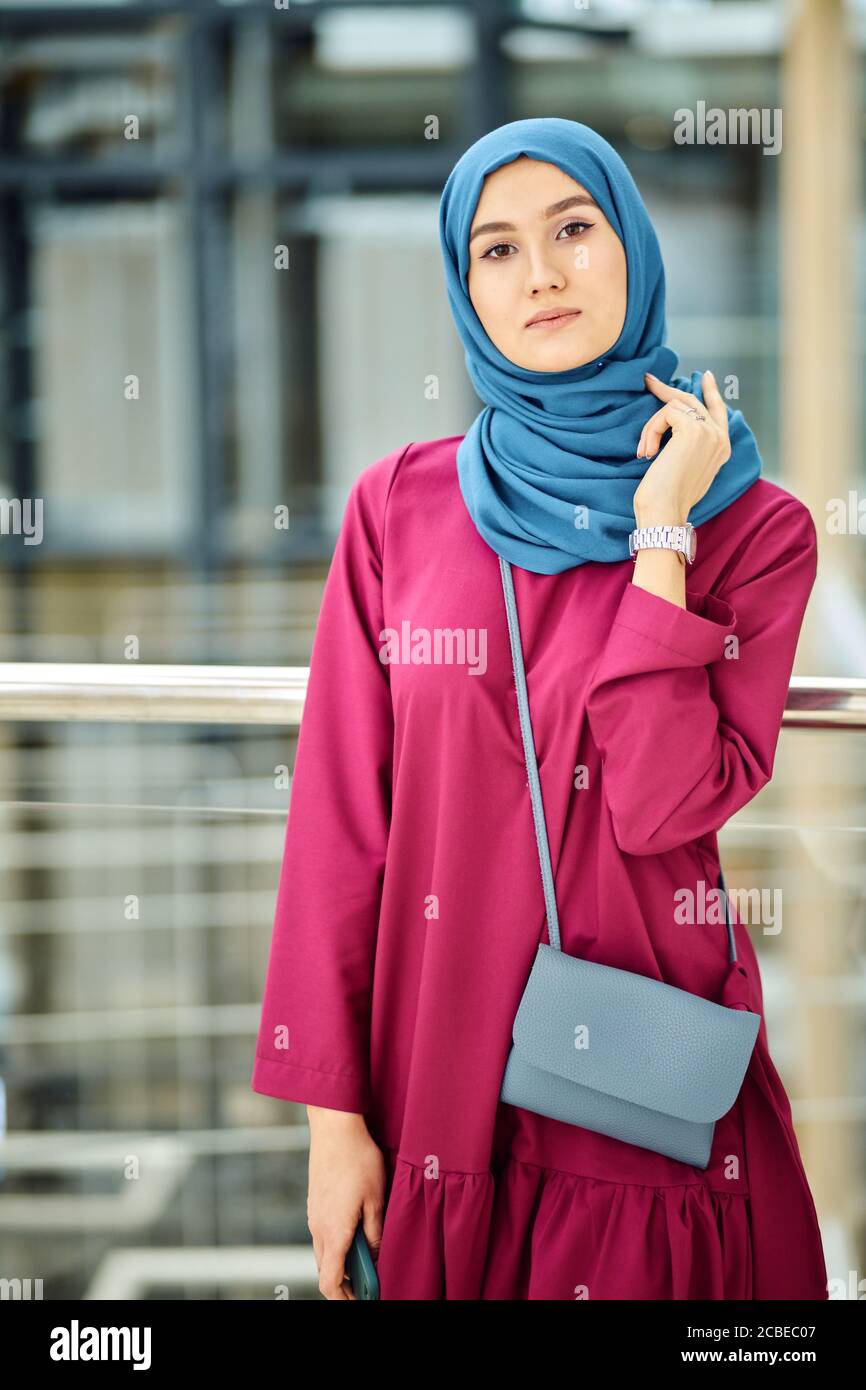 Joven hermosa mujer lleva ropa árabe tradicional de moda que consiste en  vestido largo rosa y hijab azul. Religión y Moda Fotografía de stock - Alamy