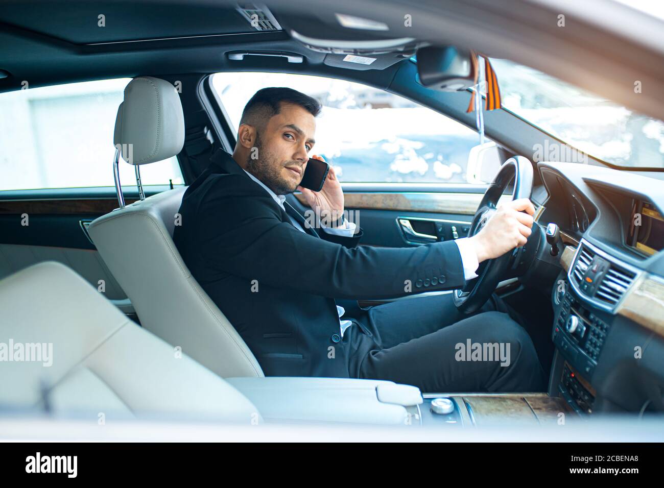 hombre de negocios hablando por teléfono sobre el trabajo y conducir un  coche, sentarse en un coche de primera clase, llevar ropa formal Fotografía  de stock - Alamy
