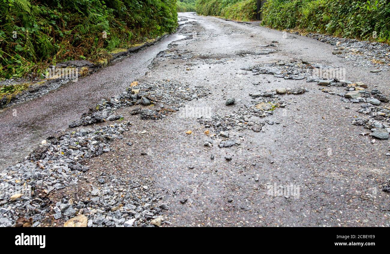 Superficie de la carretera dañada y arrastrada por las aguas pluviales Foto de stock
