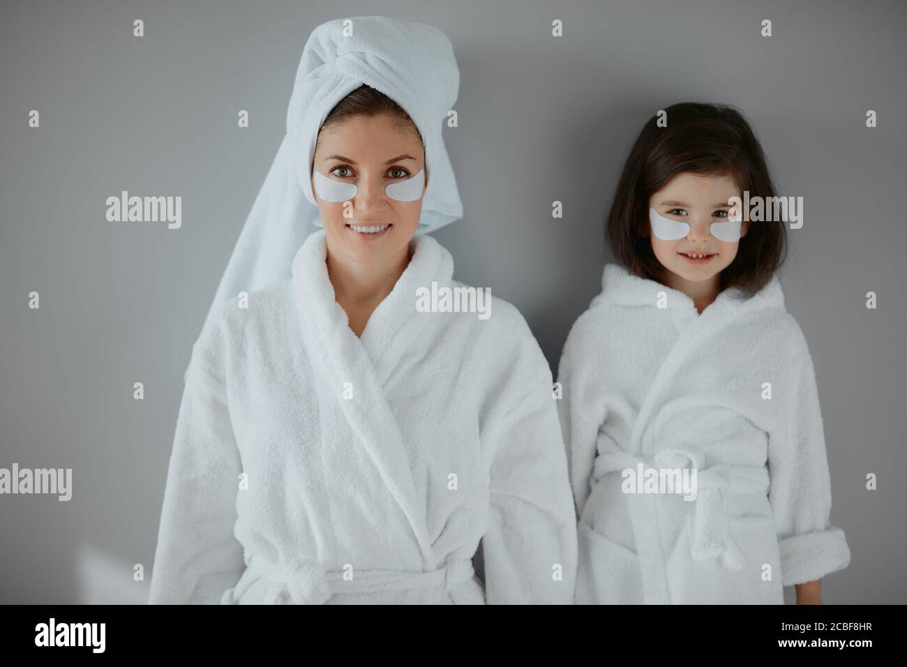 retrato de hermosa madre con su hija pequeña usando batas de baño, con  parches oculares en la cara. procedimientos de belleza con el niño  Fotografía de stock - Alamy