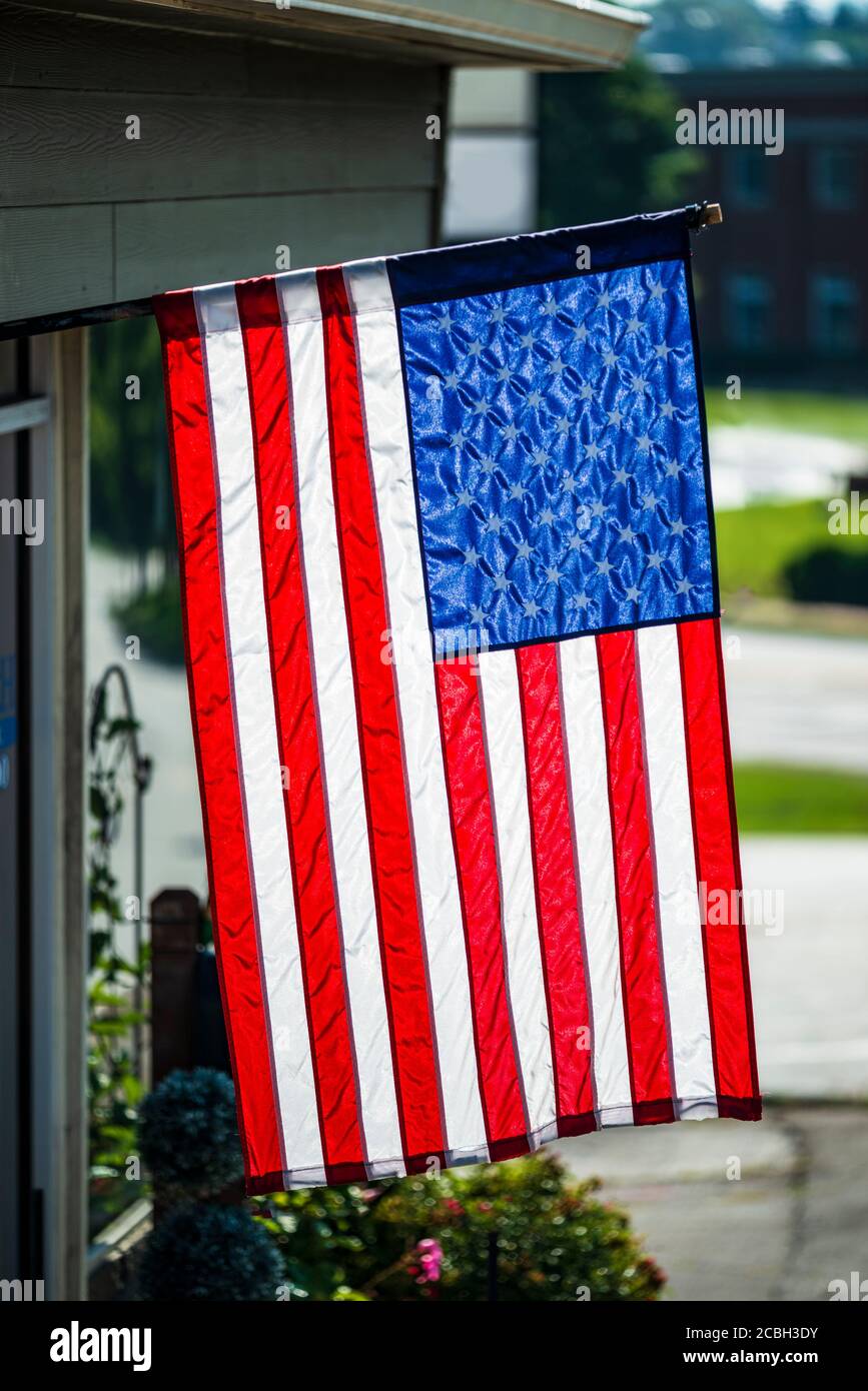 Tiro vertical de una bandera americana que cuelga verticalmente delante de un negocio. Foto de stock