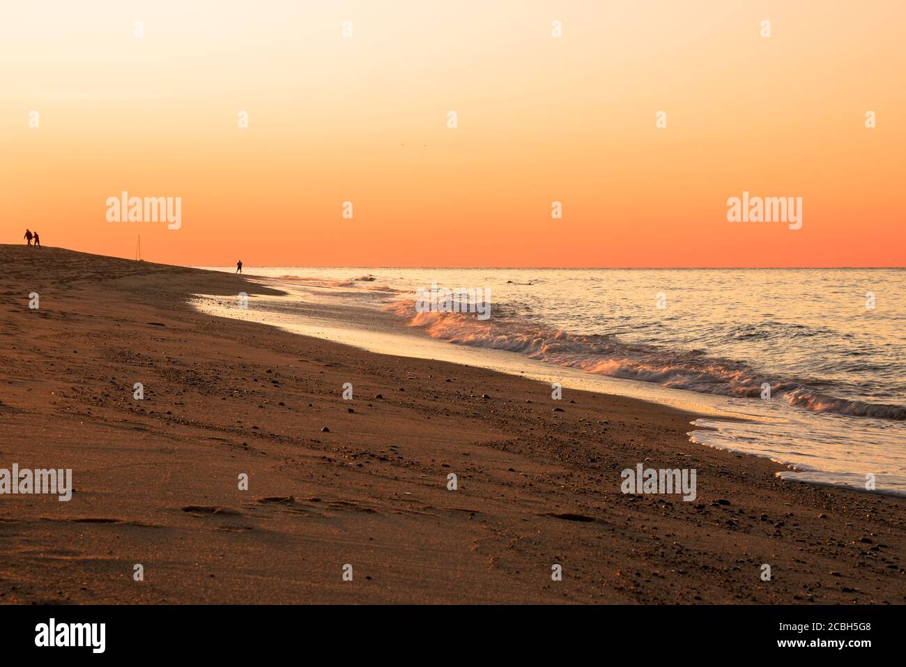 Naranja puesta de sol sobre una hermosa gran playa de arena en otoño Foto de stock