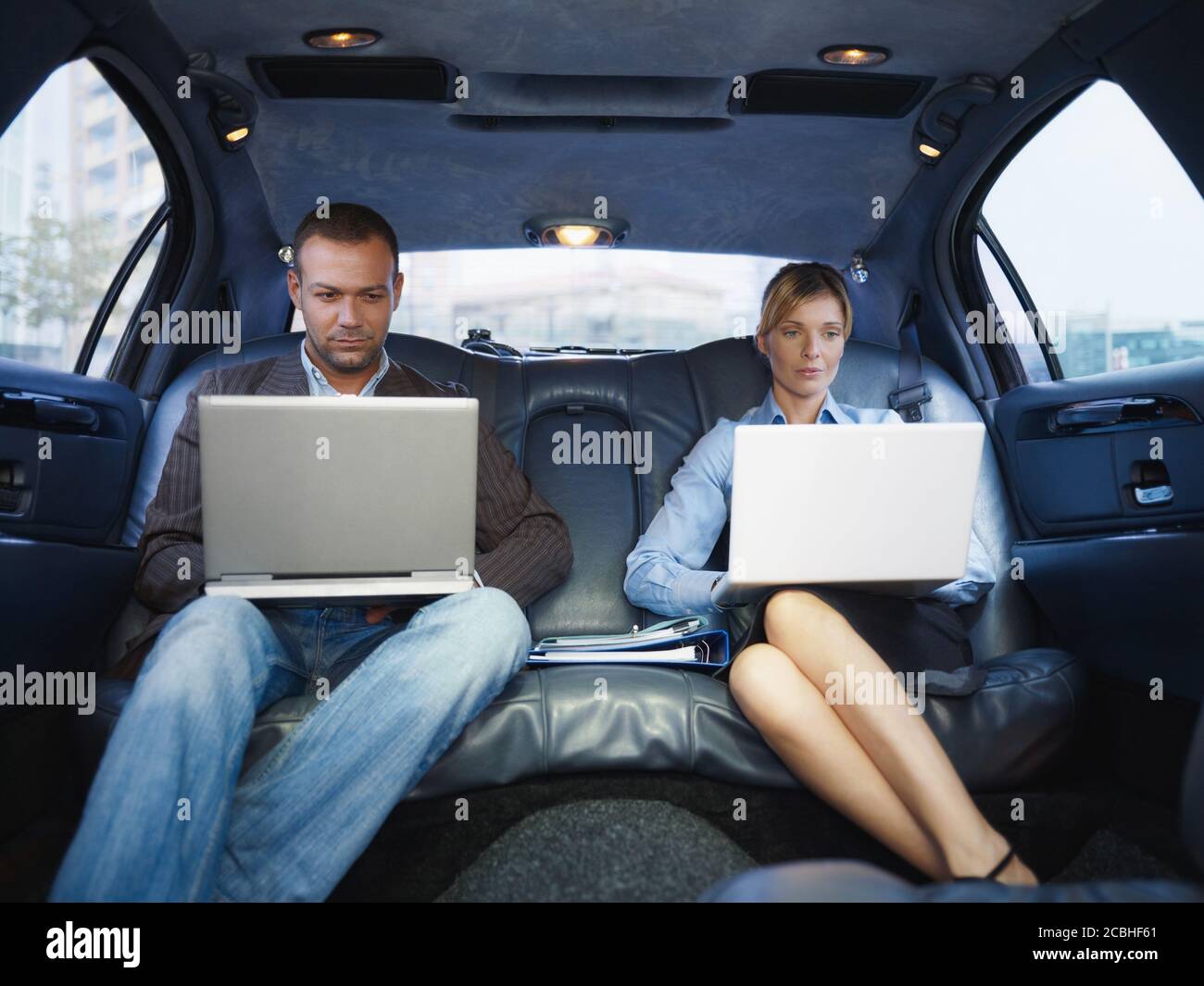 Hombre y mujer de negocios trabajando con ordenador portátil en limusina Foto de stock